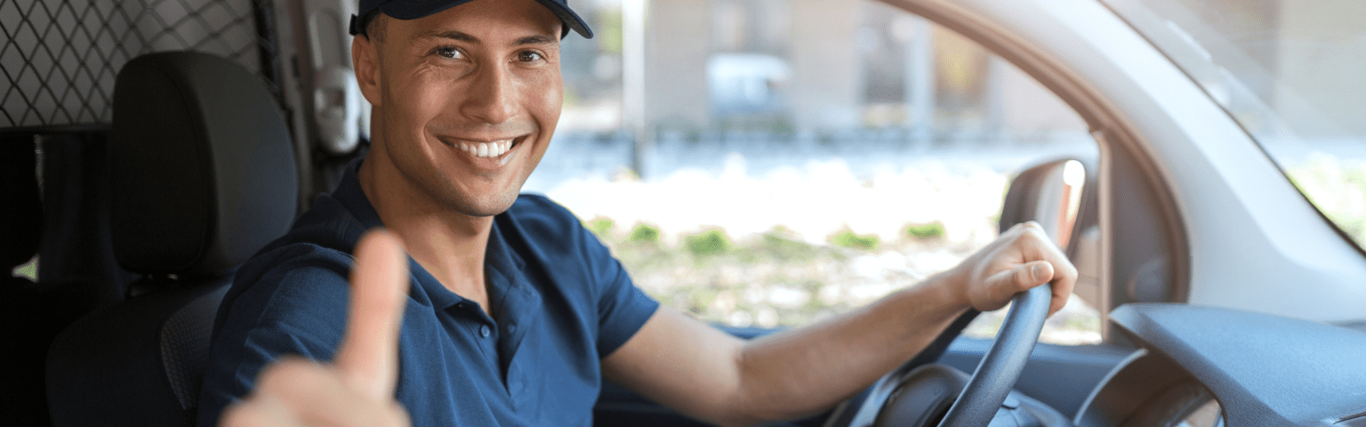 delivery driver behind the wheel of delivery van giving a thumbs up