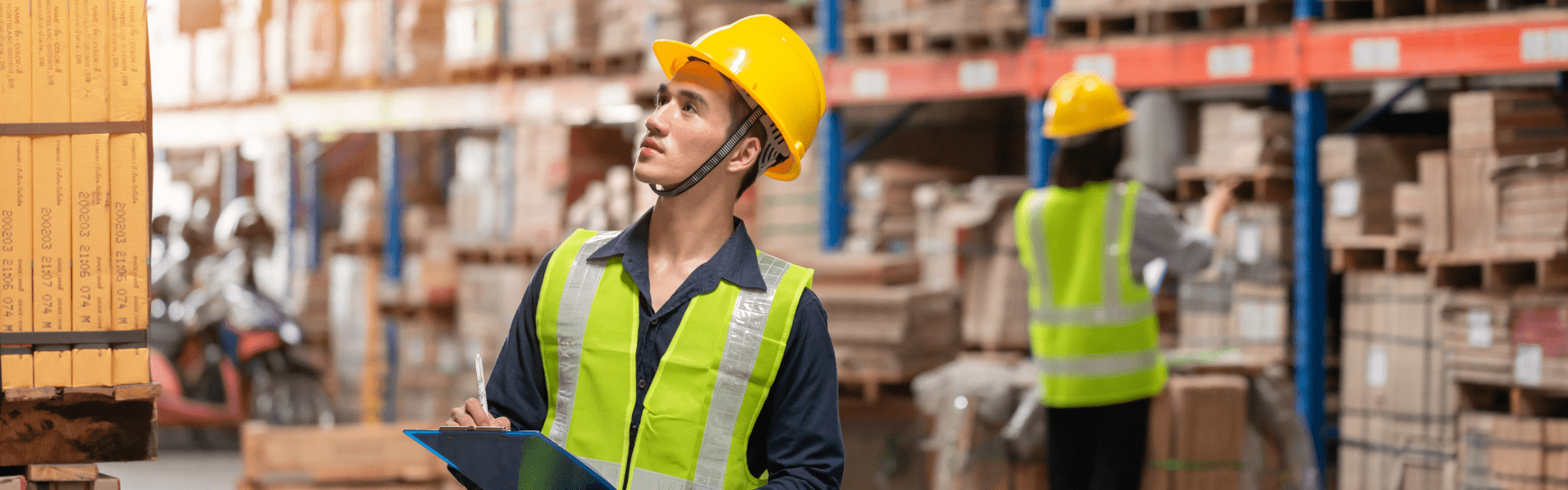 workers with yellow safety vests and hard hats holding clipboards in warehouse full of boxes, NYC microhub for final mile deliveries
