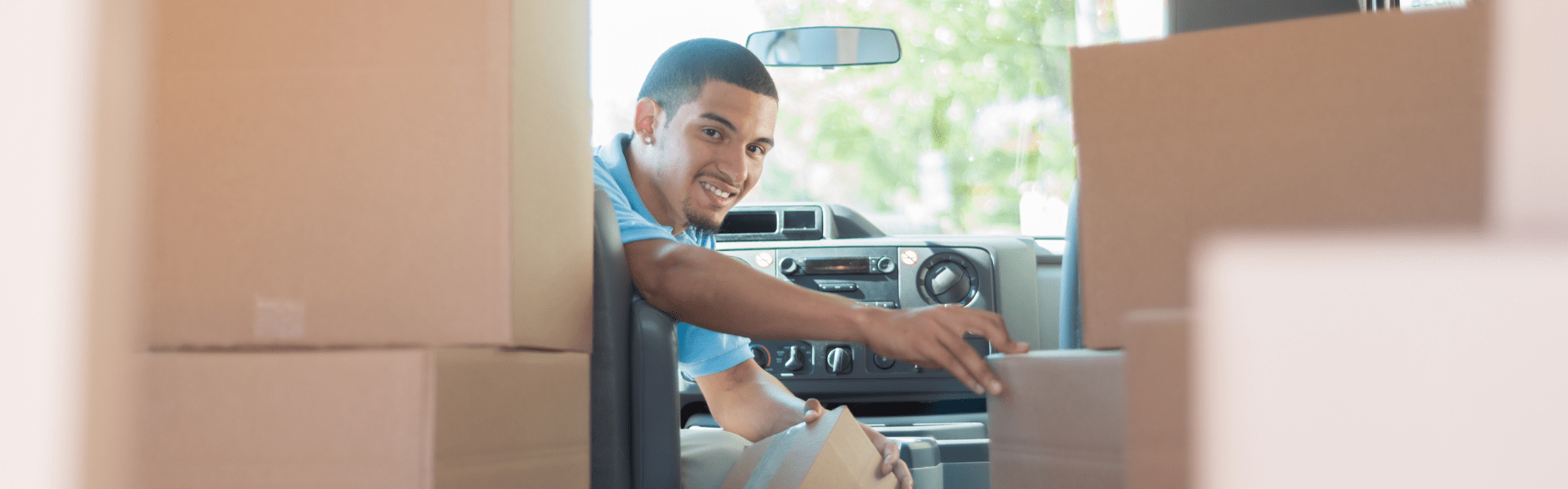 package delivery driver in package delivery truck looking back though boxes of packages loaded in the back of the truck