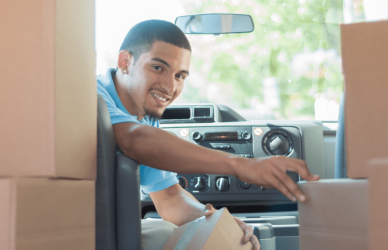 package delivery driver in package delivery truck looking back though boxes of packages loaded in the back of the truck